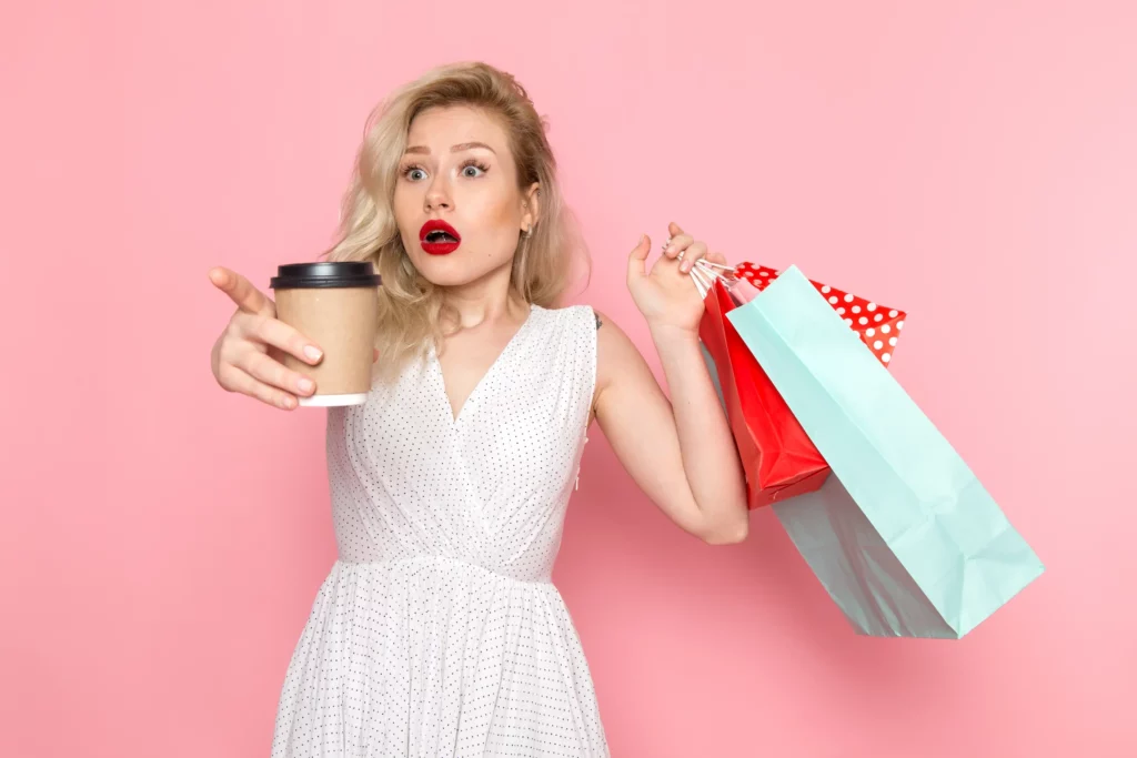 Image - Une femme fait du shopping en portant un café à la main.